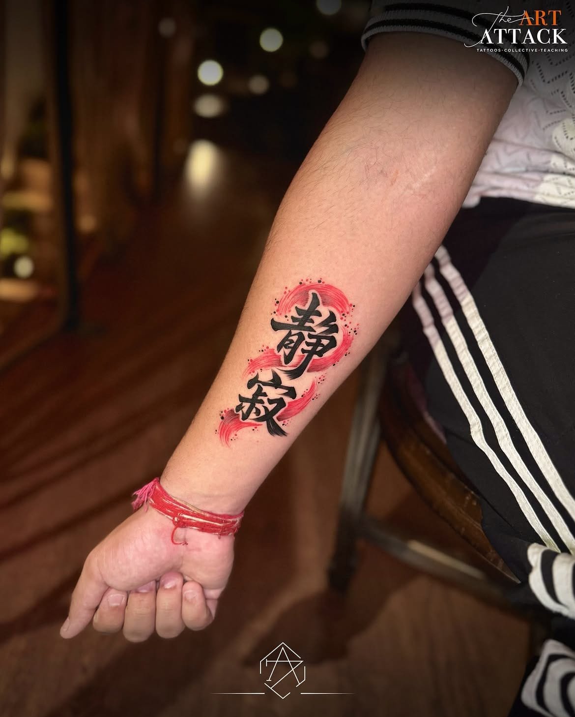 Butterfly tattooed on a forearm beneath a red crescent moon.