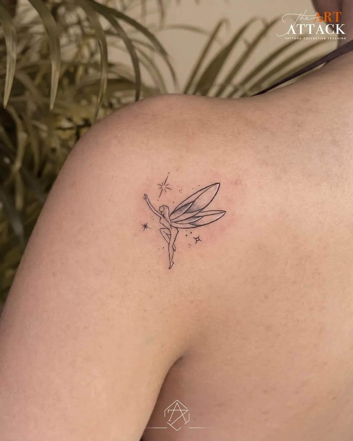 Small fine-line figure tattooed on a shoulder blade.
